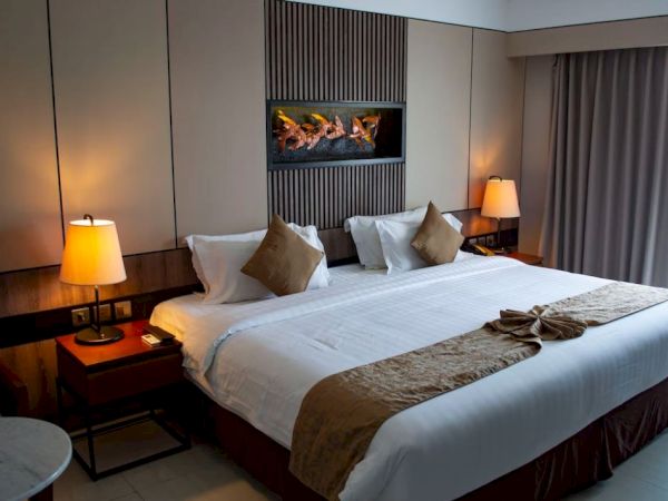 A neatly arranged hotel room with a large bed, bedside lamps, throw pillows, decorative items, and a window with curtains.
