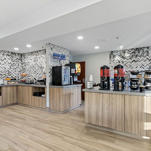 The image shows a modern breakfast buffet area with coffee machines, dispensers, and various food items on wooden counters with patterned walls.