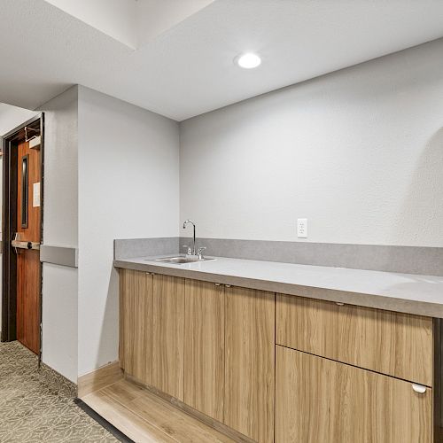 The image shows a room with a countertop and cabinets, stacked chairs, an American flag, and two doors, one partially open.