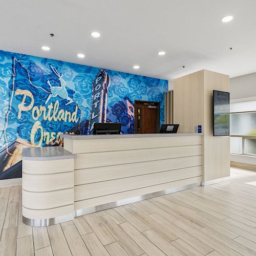 A modern reception area features a front desk, a mural with 