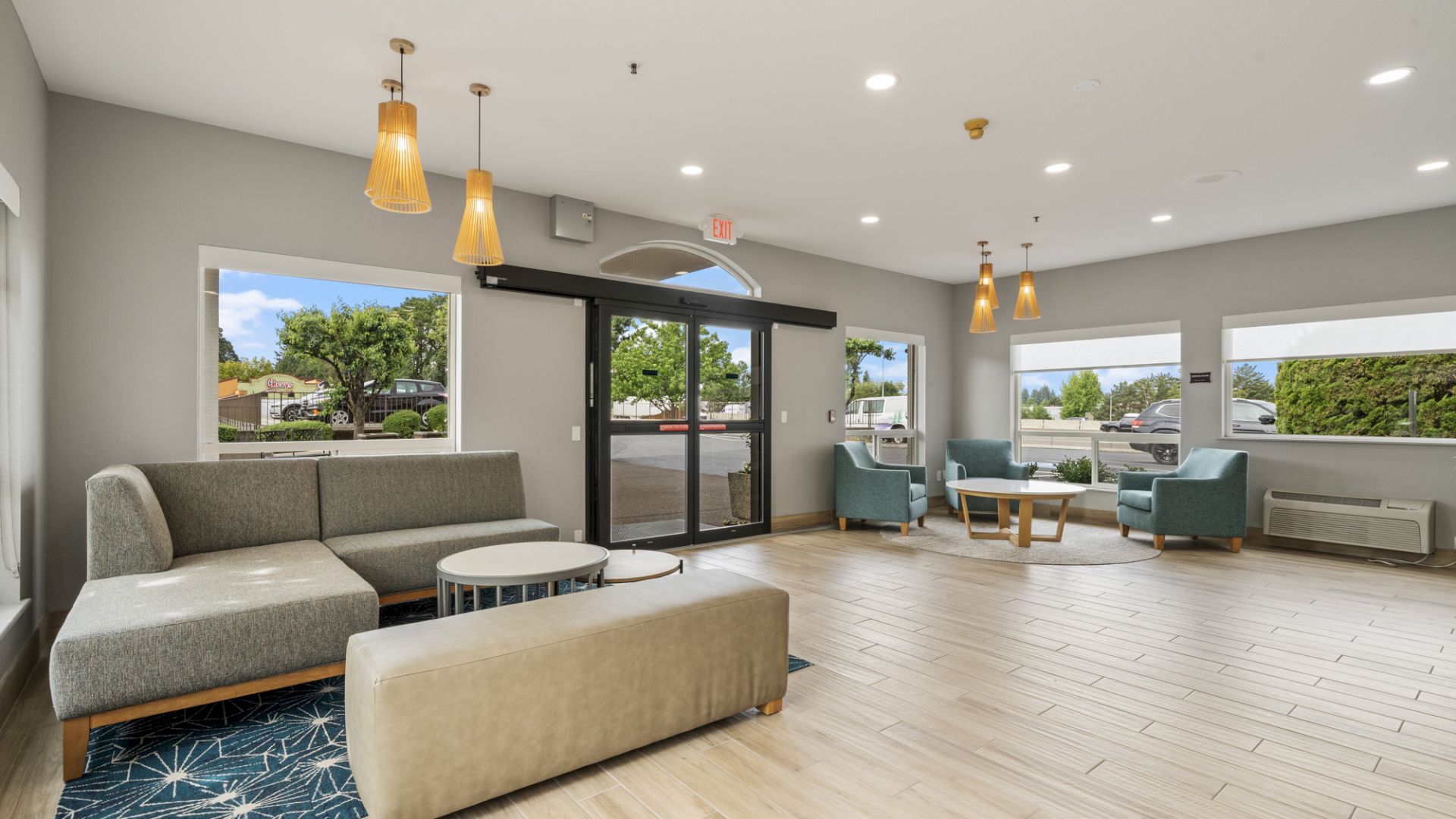 A modern, spacious lobby with contemporary seating, large windows, and hanging lights. Bright, open design with a welcoming atmosphere.