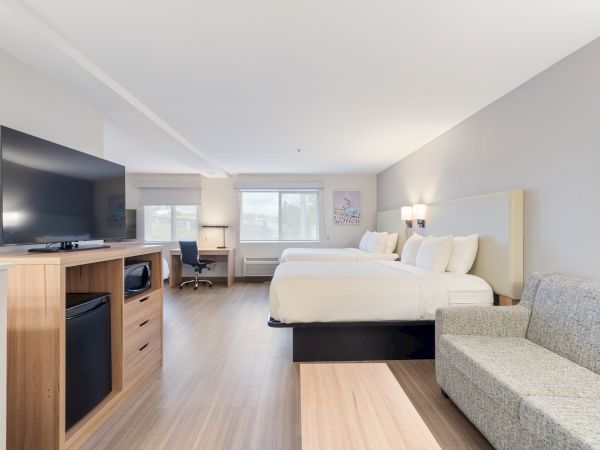 A modern hotel room with two beds, a sofa, a desk, a TV, and a large window, featuring a clean and minimalistic design, ending the sentence.